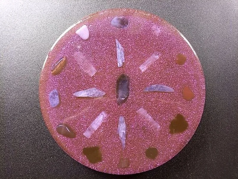 Violet orgone plate with clear quartz in the center on a black background.